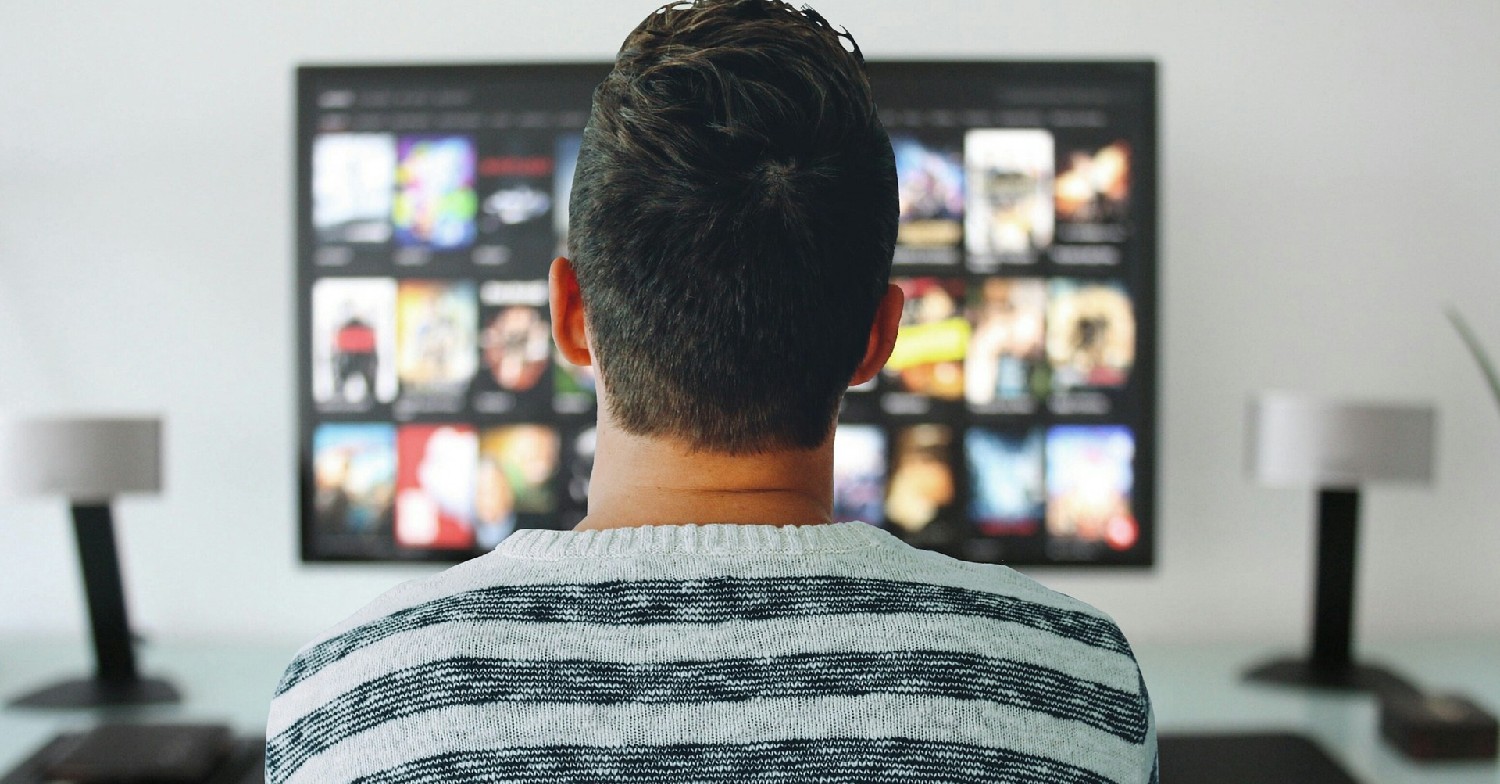 Man with his back to camera, watching TV