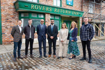 Princess Anne stands on the Corrie set with the show's producers and members of the cast