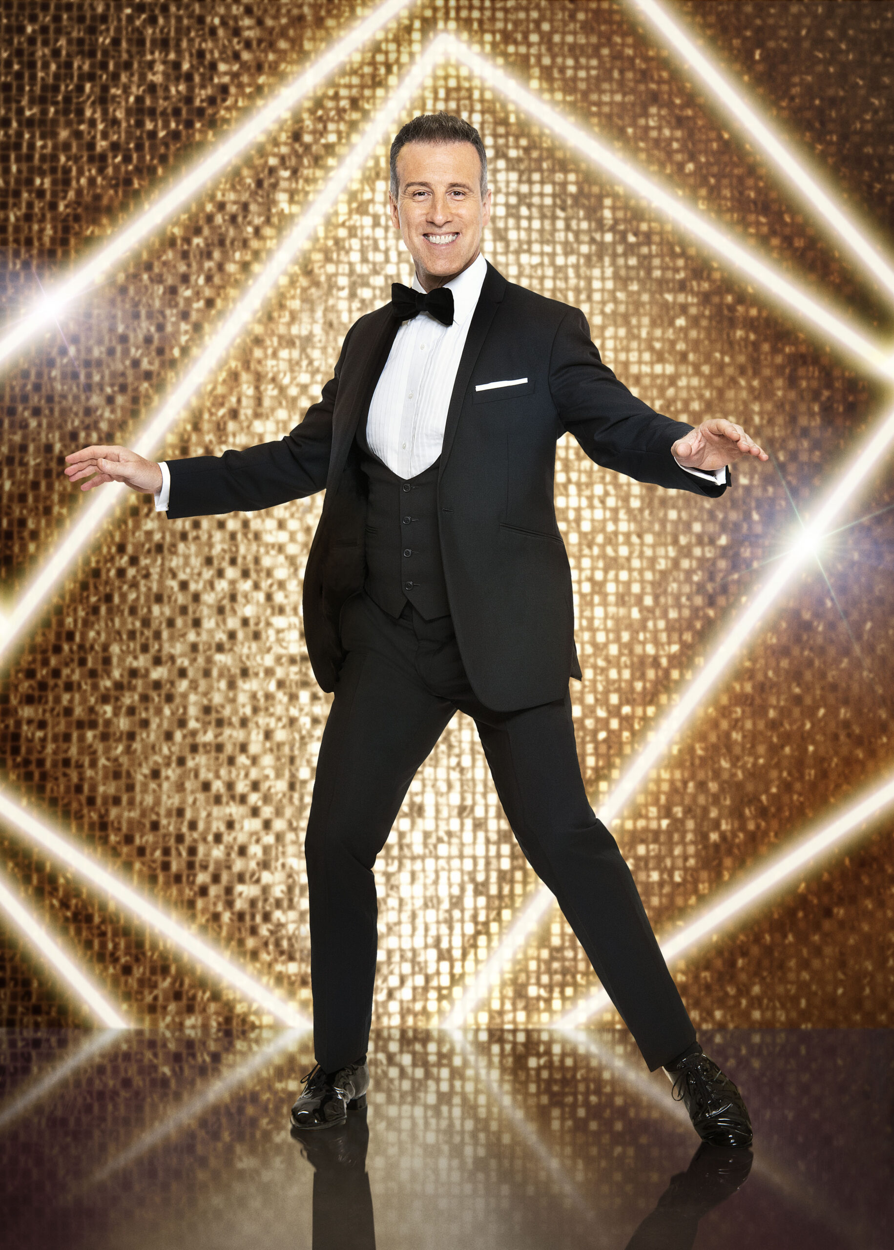 Anton Du Beke smiling in front of a gold glitter wall