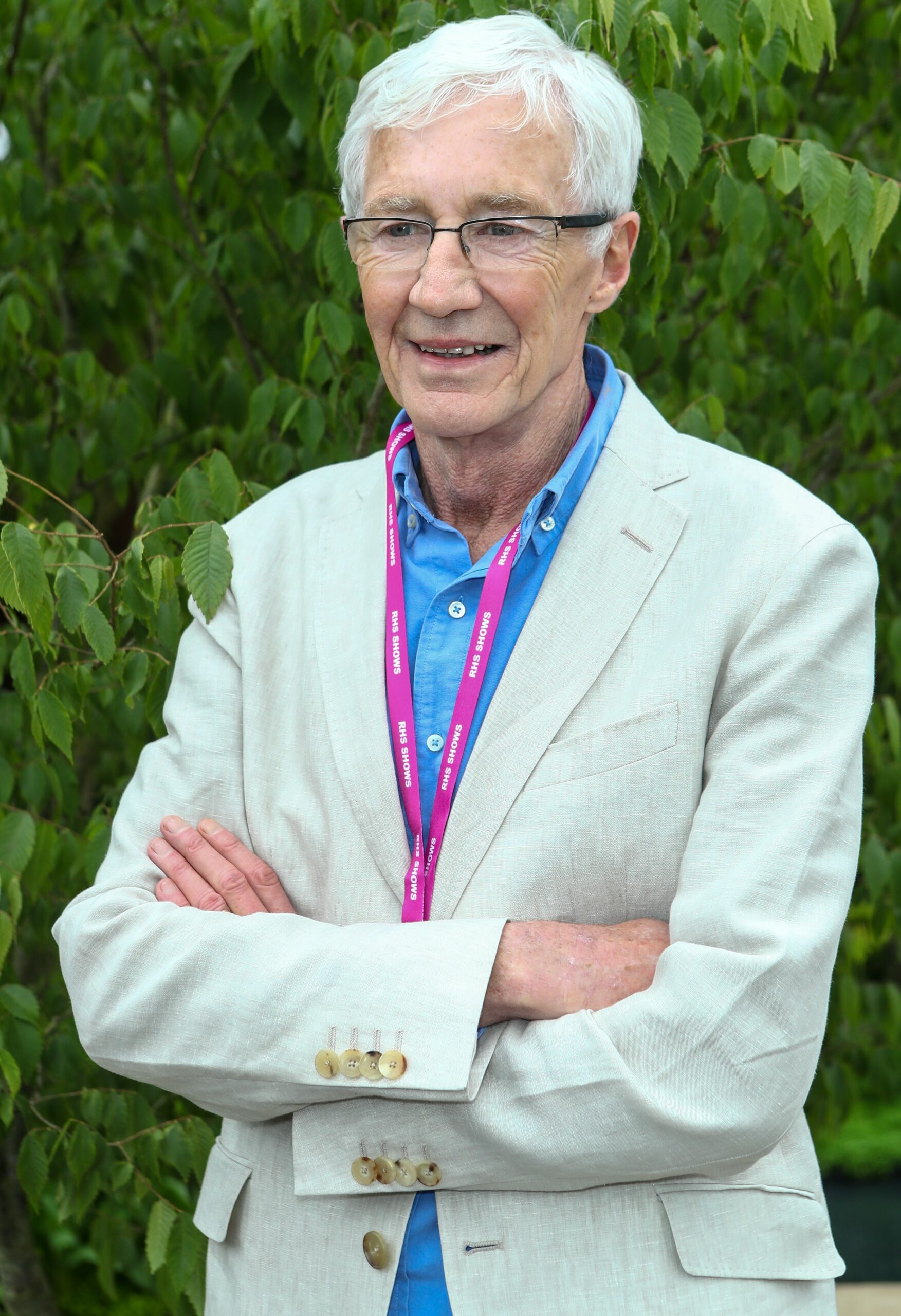 Paul O'Grady smiling with his arms folded at Chelsea Flower Show