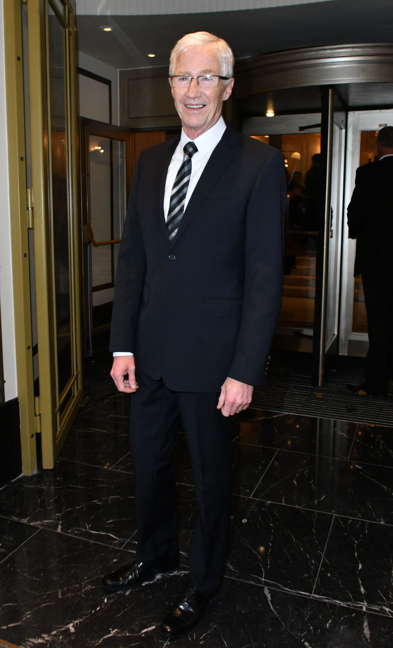 Paul O'Grady smiles as he leaves hotel 
