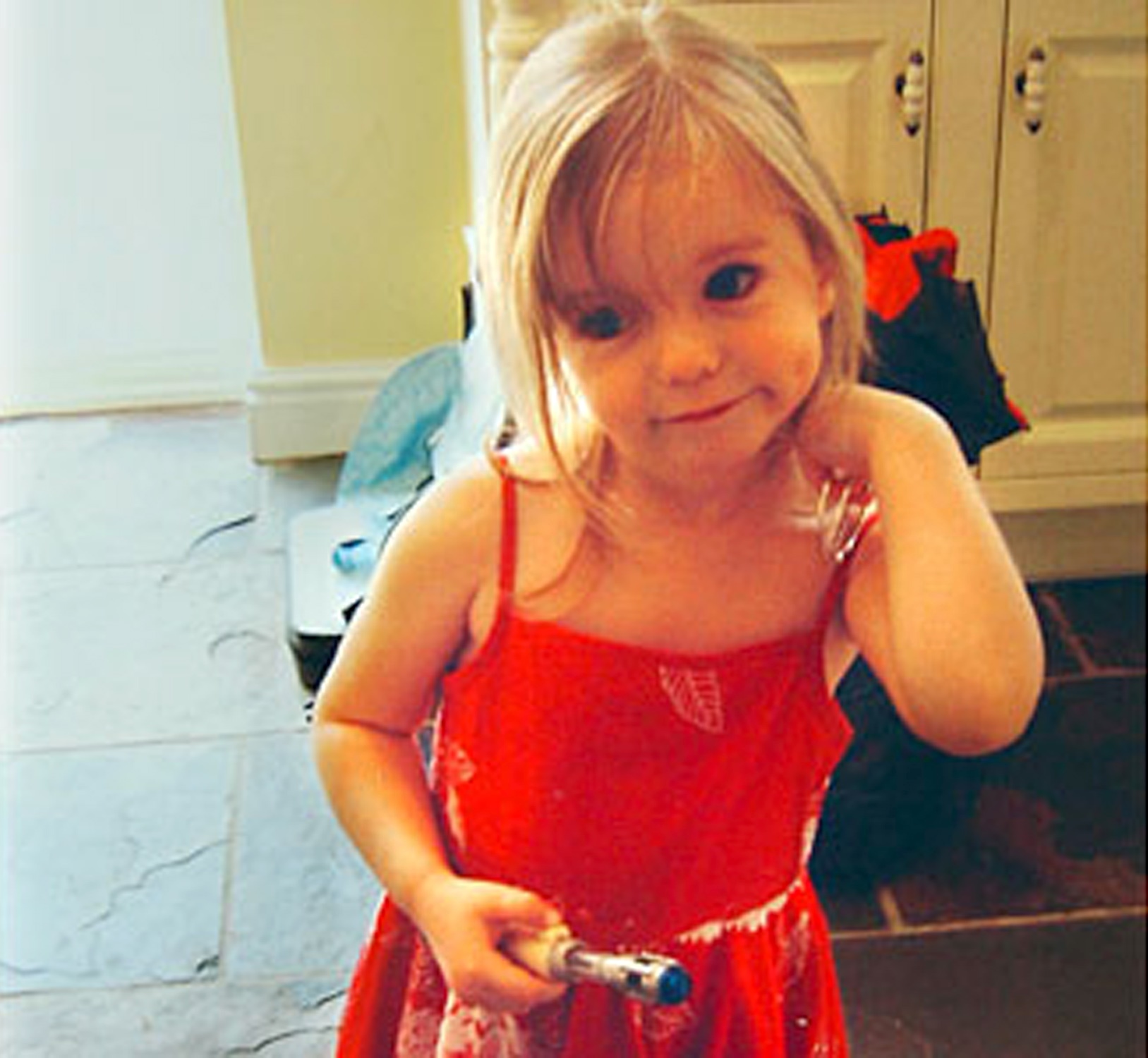 Madeleine McCann smiles sweetly in a red dress