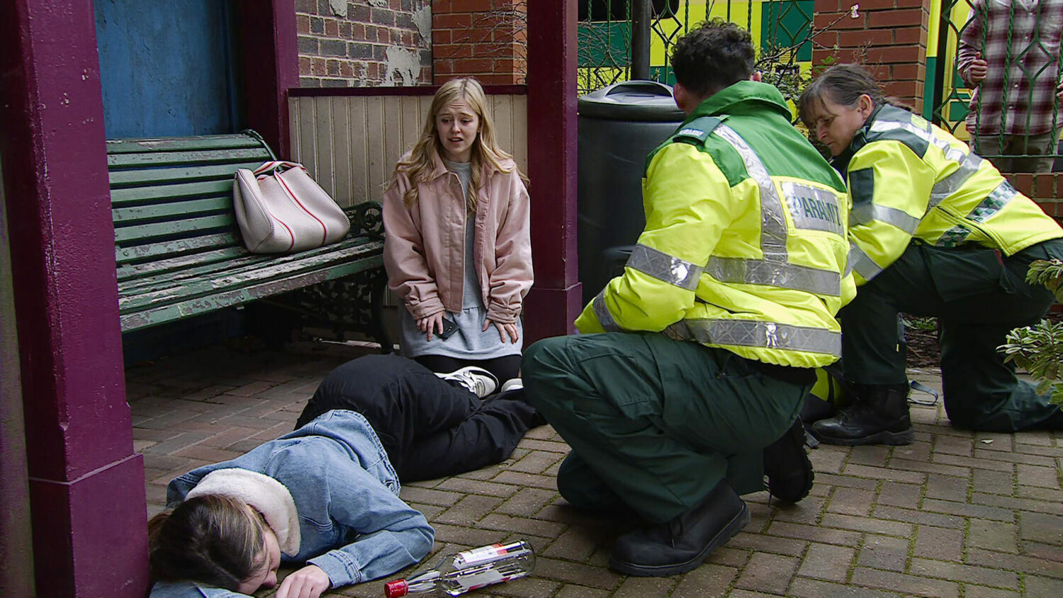 Summer is looking at an unconscious Amy with worry alongside the paramedics