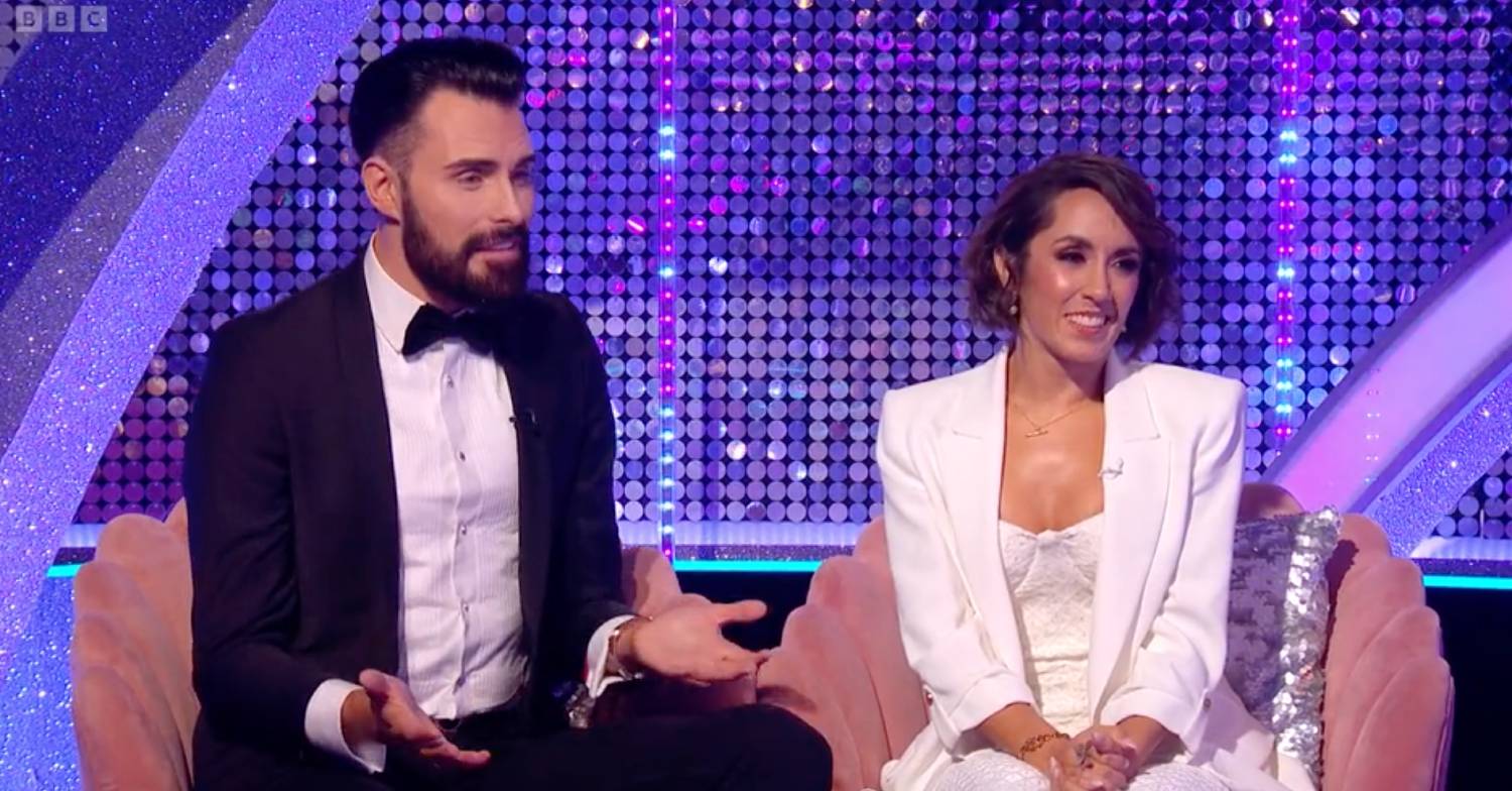 Rylan holds open his palms as he sits next to Janette Manrara