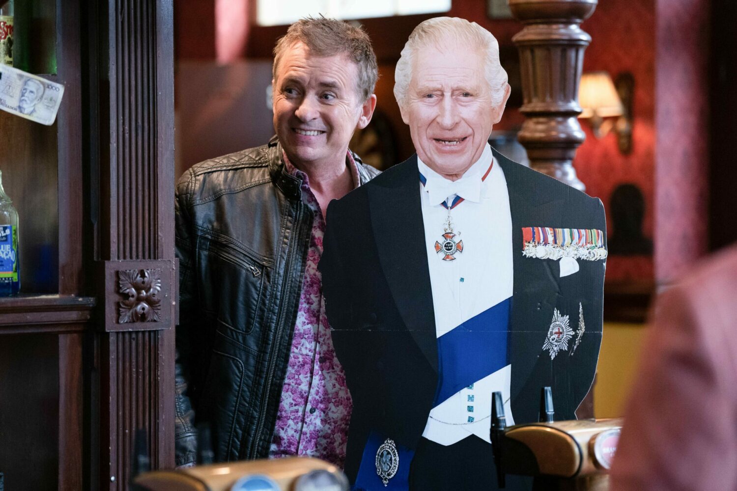 Alfie Moon smiles next to a life-size cardboard cutout of King Charles