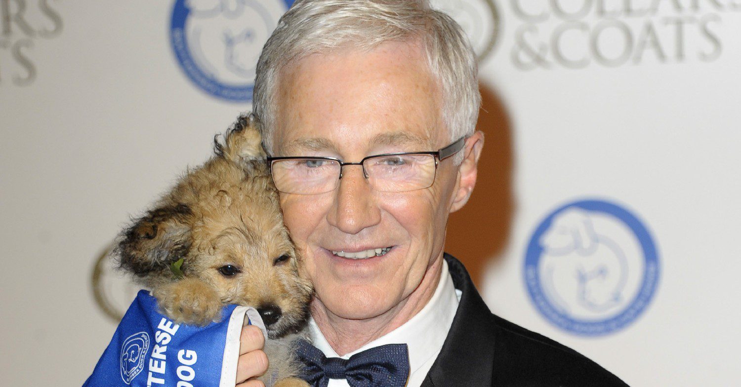 Paul O'Grady smiling holding a dog 
