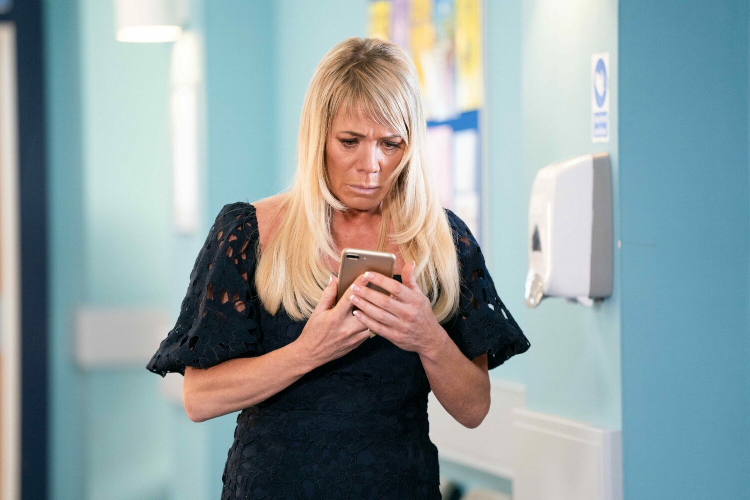 Sharon in EastEnders stares worriedly at her phone