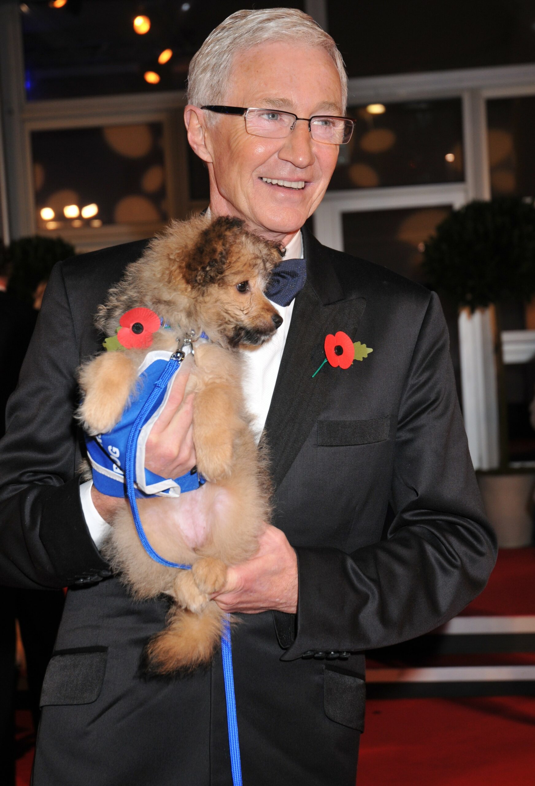 Paul O'Grady holding a dog at event