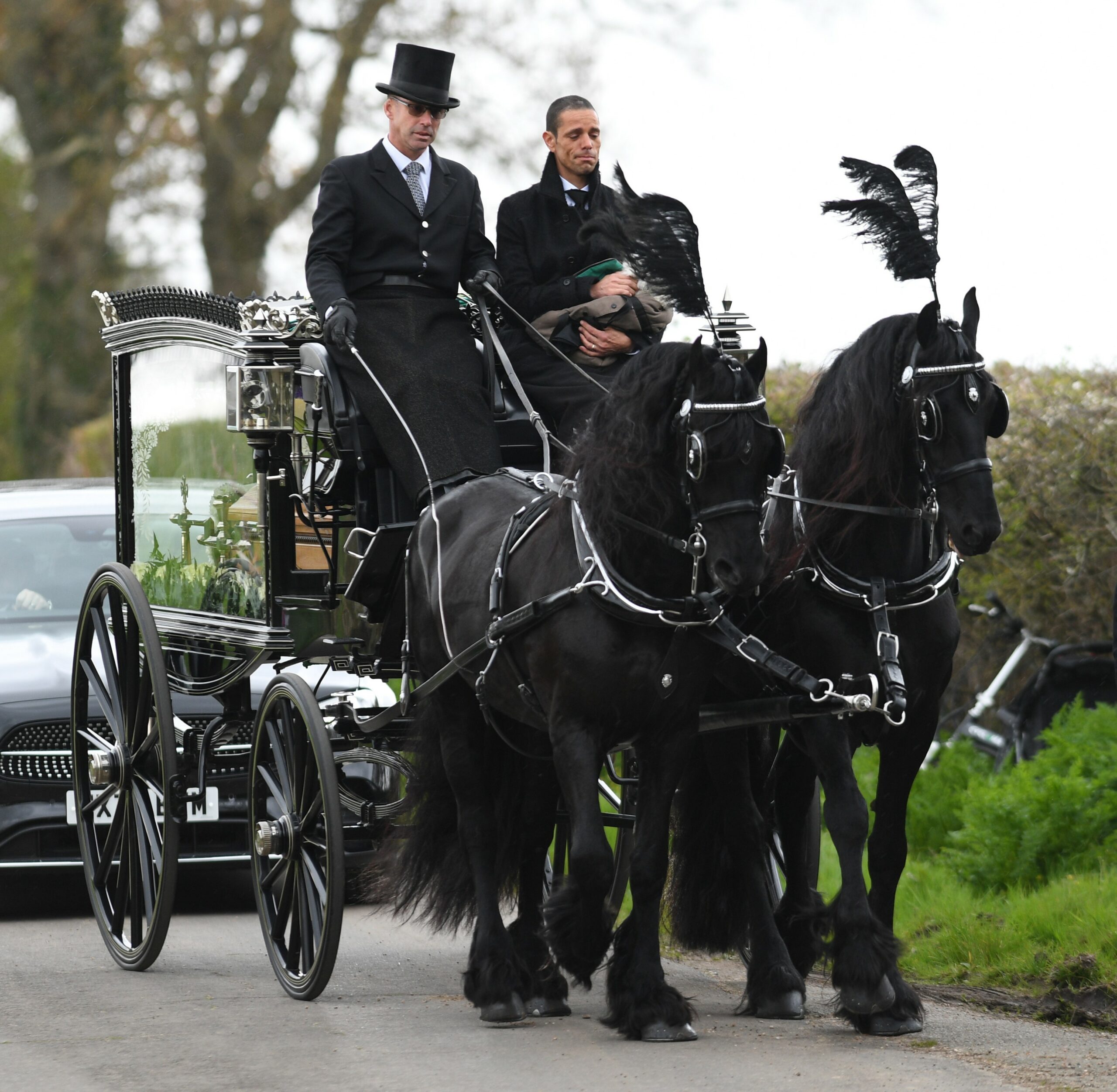 Paul O'Grady funeral as his husband sits on carriage carrying his coffin