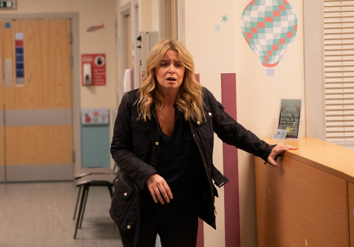 Charity looks shocked and horrified in a hospital corridor on Emmerdale