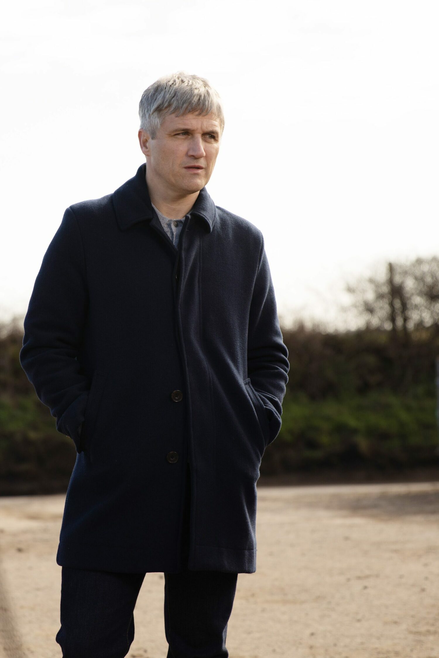 Caleb in Emmerdale watches on from a distance, looking interested and like he's plotting