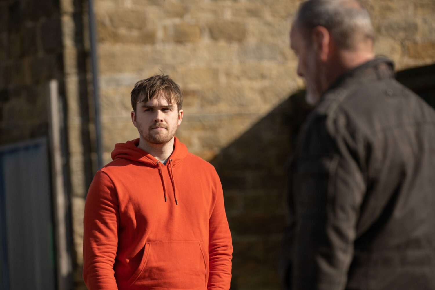 Tom King in Emmerdale looks thoughtful as he stares into the distance with Jimmy also in shot