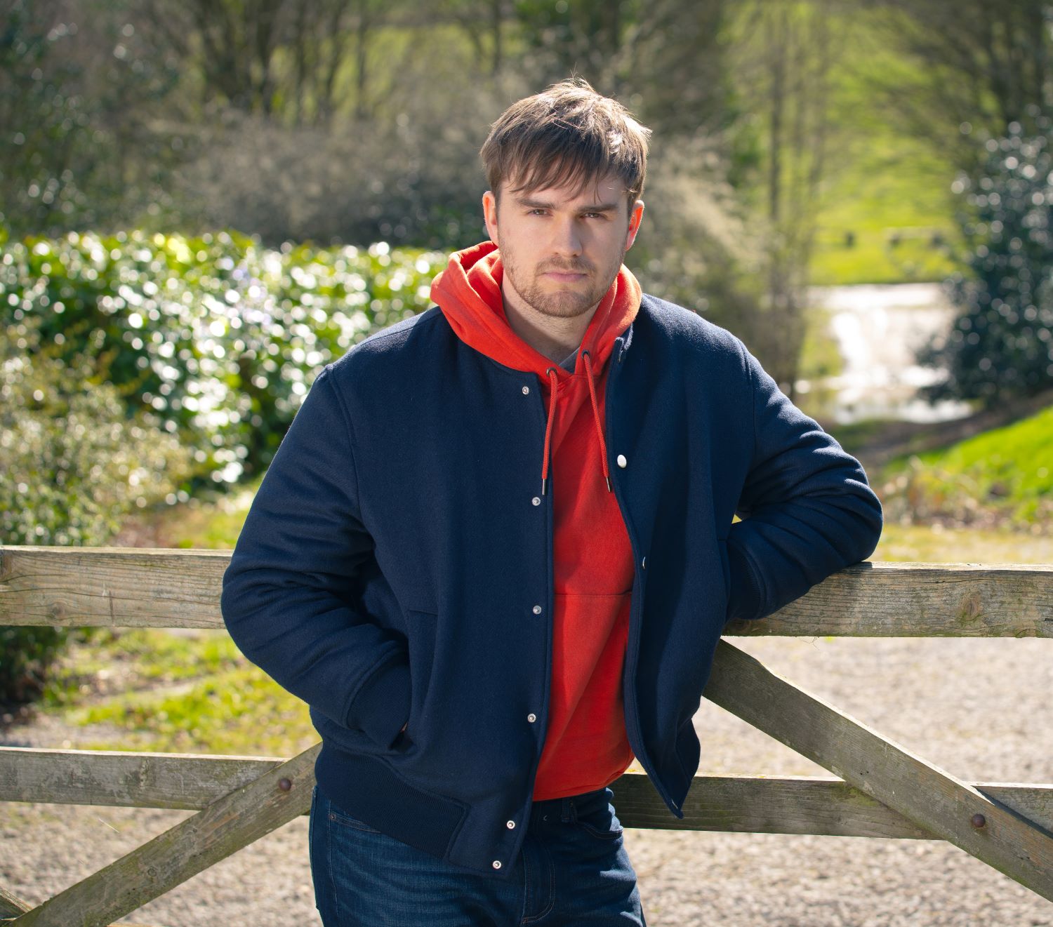 Tom King in the Emmerdale cast leans on a gate looking mean and moody