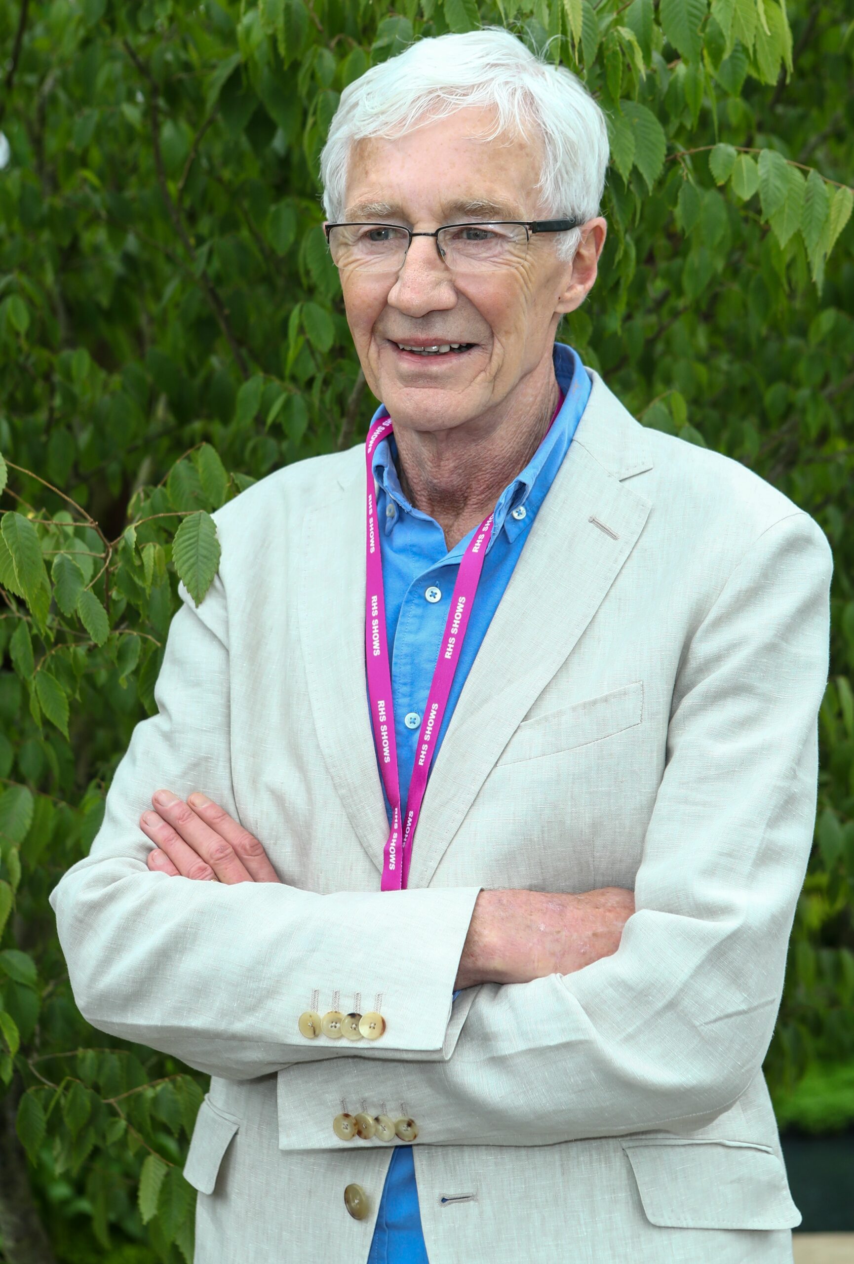 Paul O'Grady smiling with arms crossed at Chelsea Flower Show