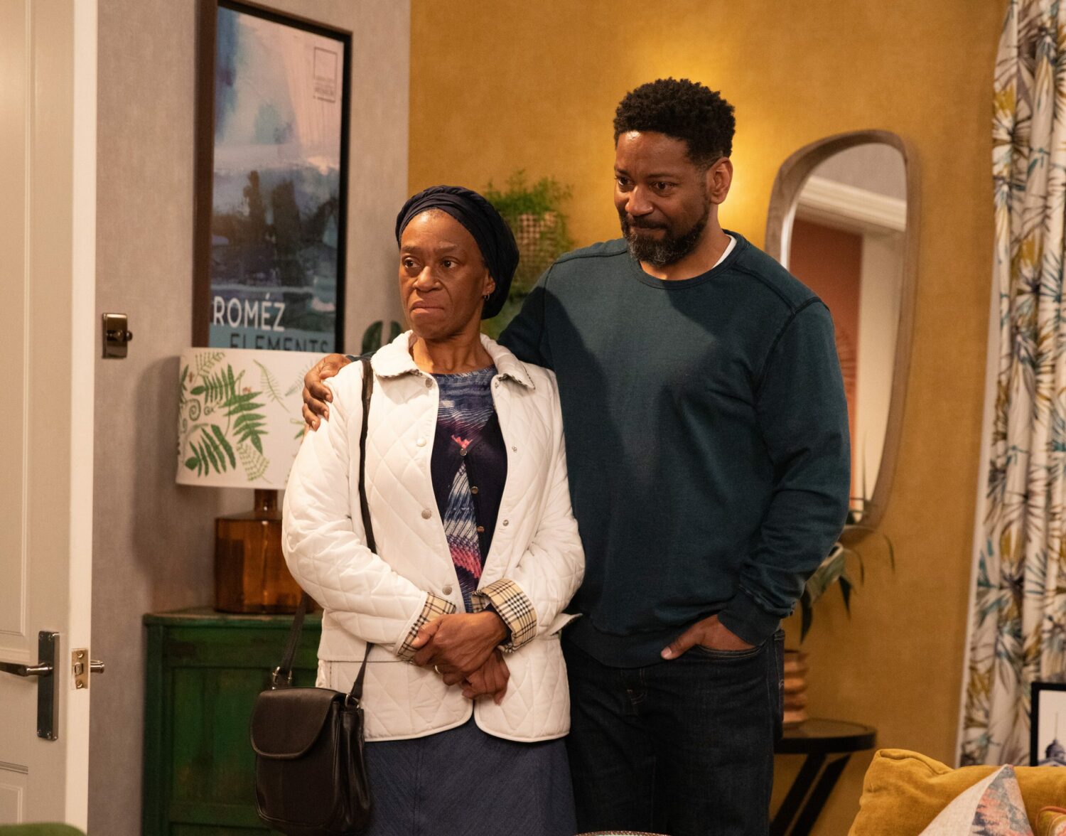 Claudette in Emmerdale look unimpressed as Charles looks anxious with his arm around her