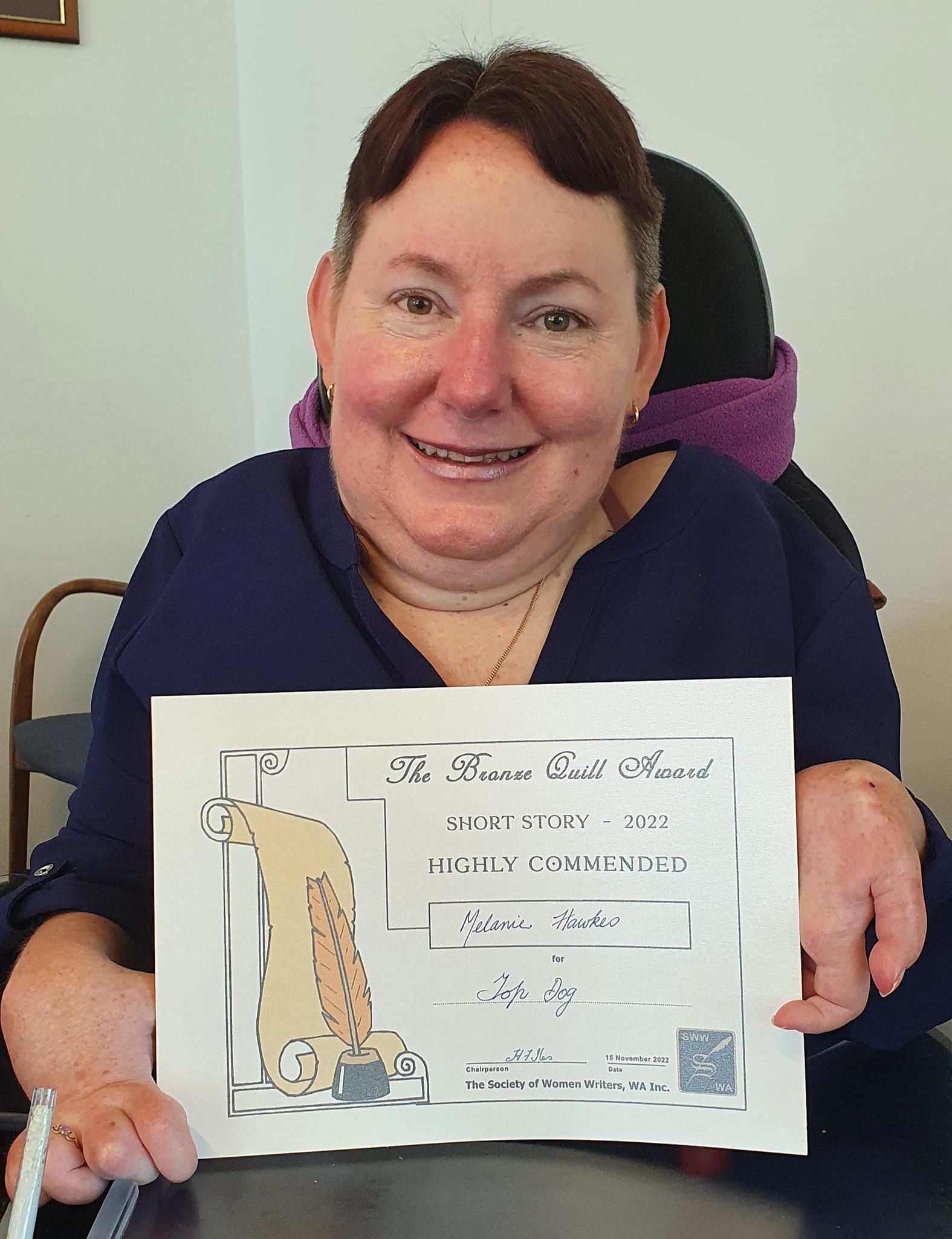 Melanie Hawkes smiles with certificate