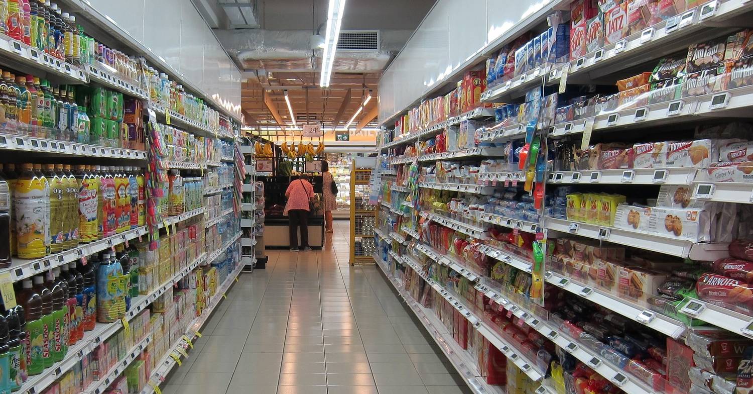 Woman inspects food in a supermarket aisle