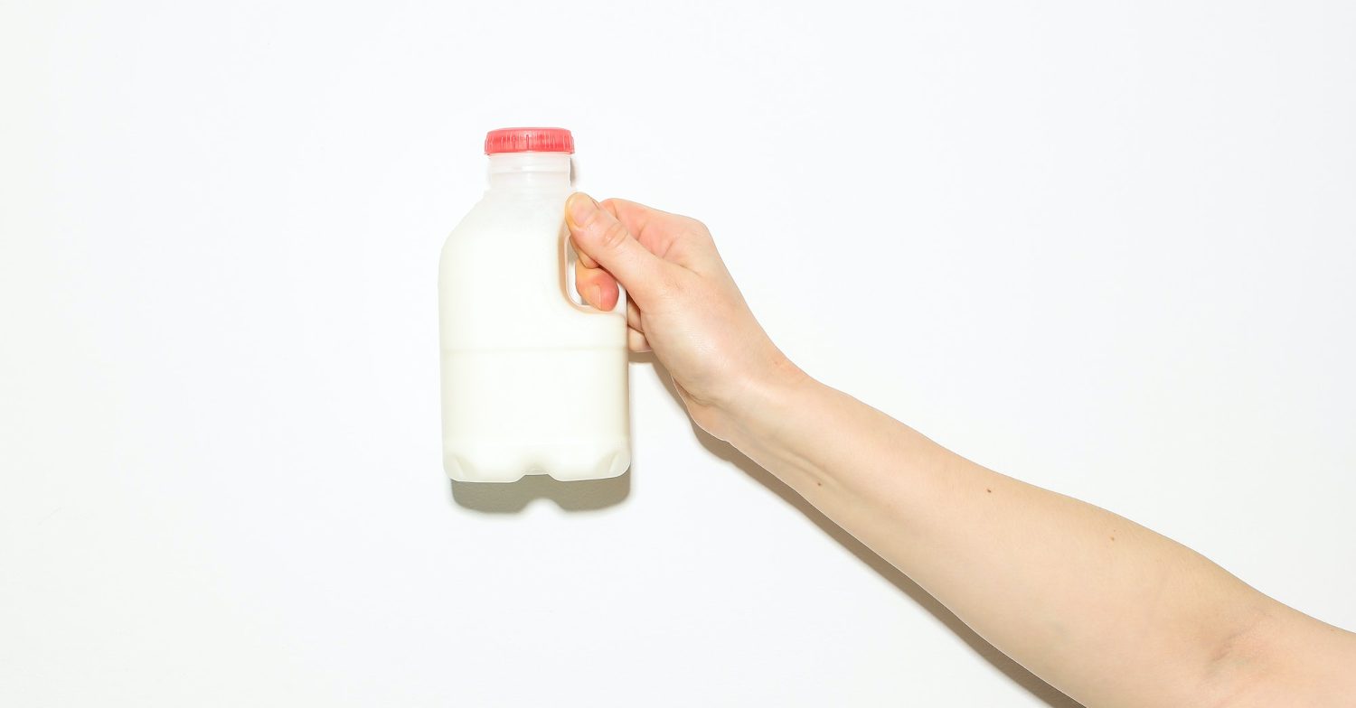 A hand holds up a small carton of milk