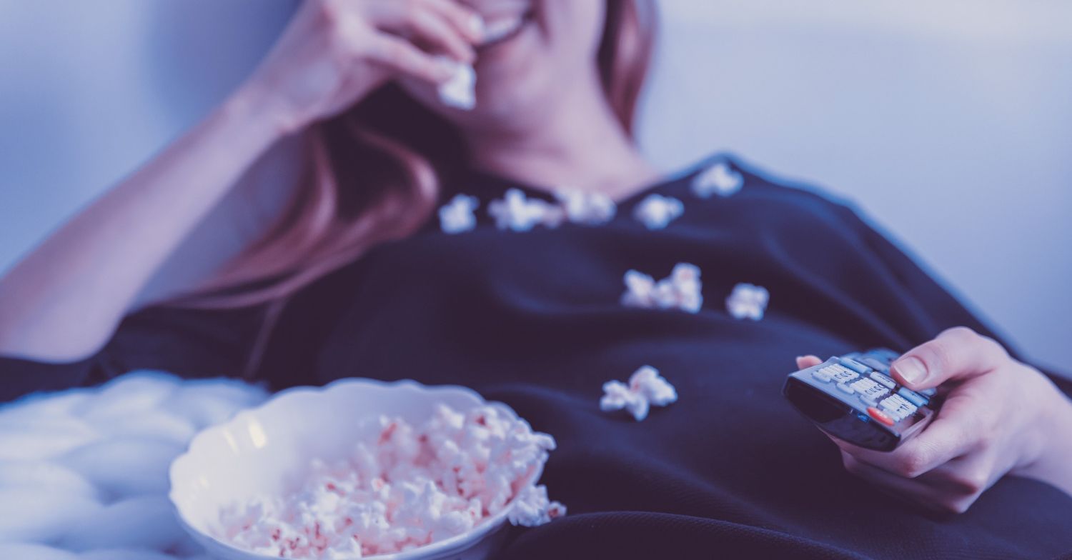 Woman watching TV with popcorn.