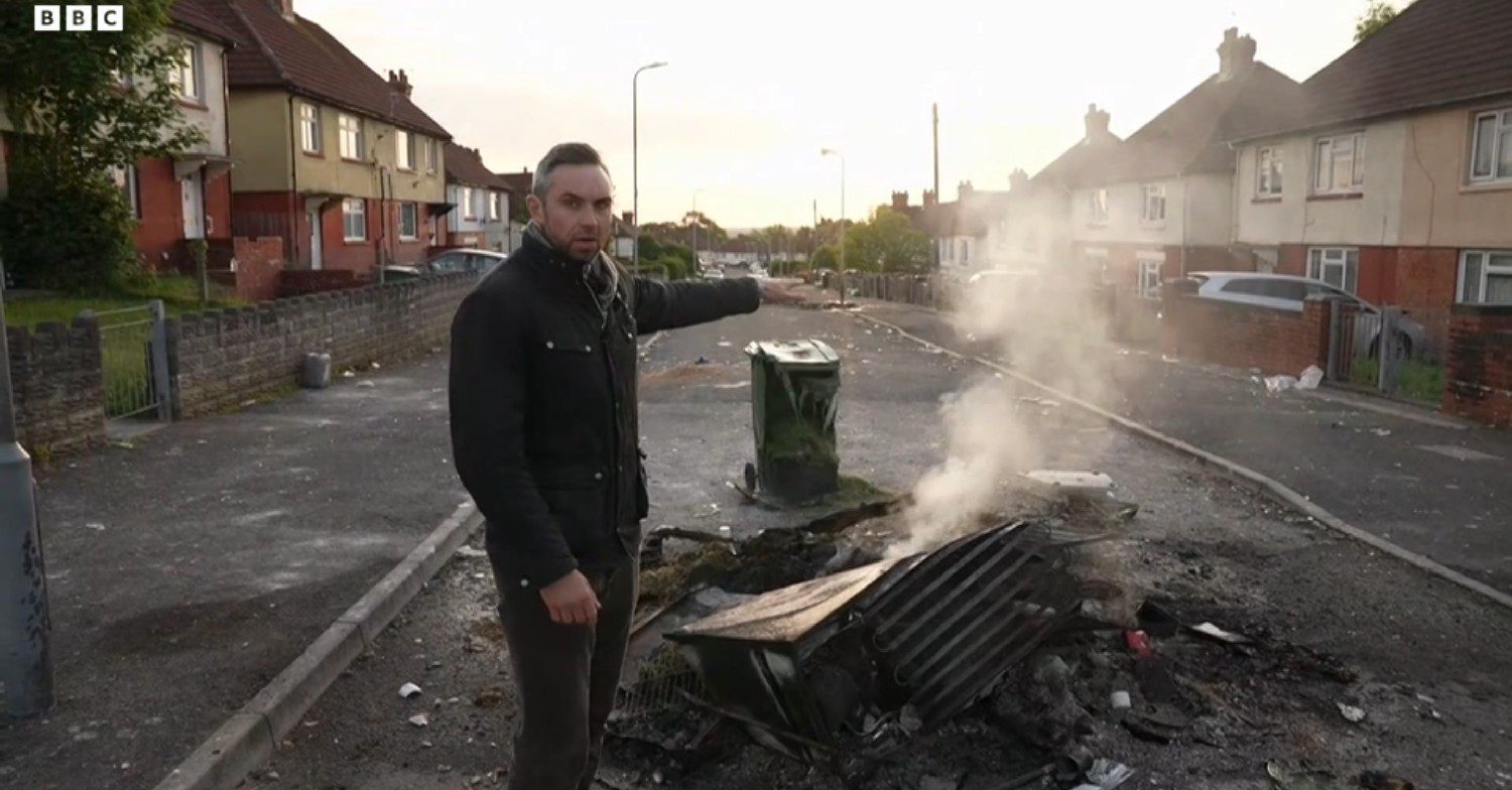 Reporter in front of smoking remains in Cardiff