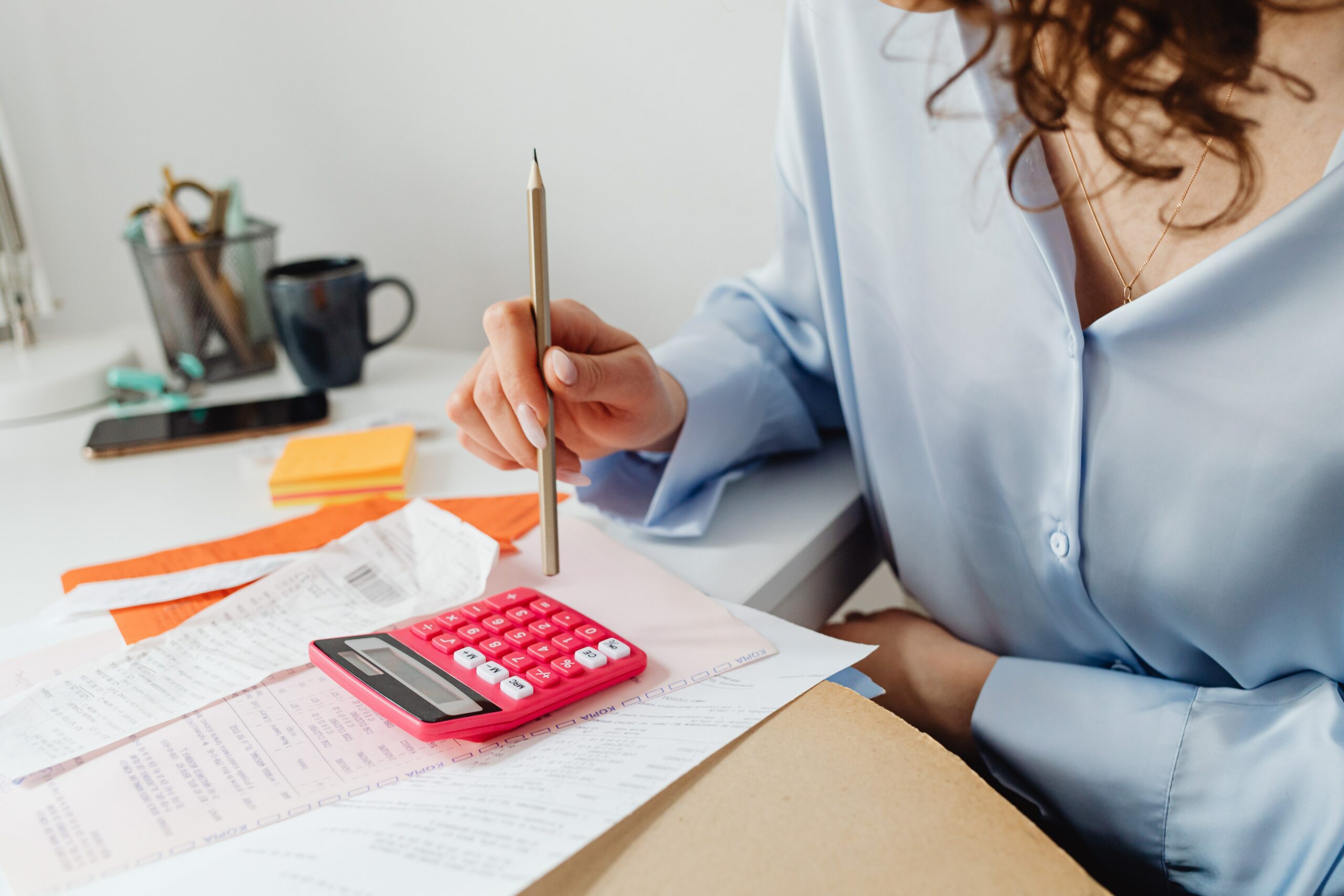 A woman sits with a calculator and bills