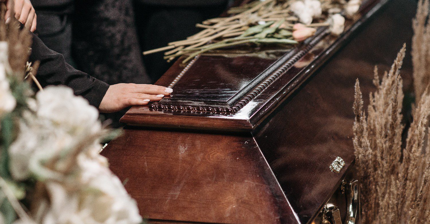 People placing hand on coffin