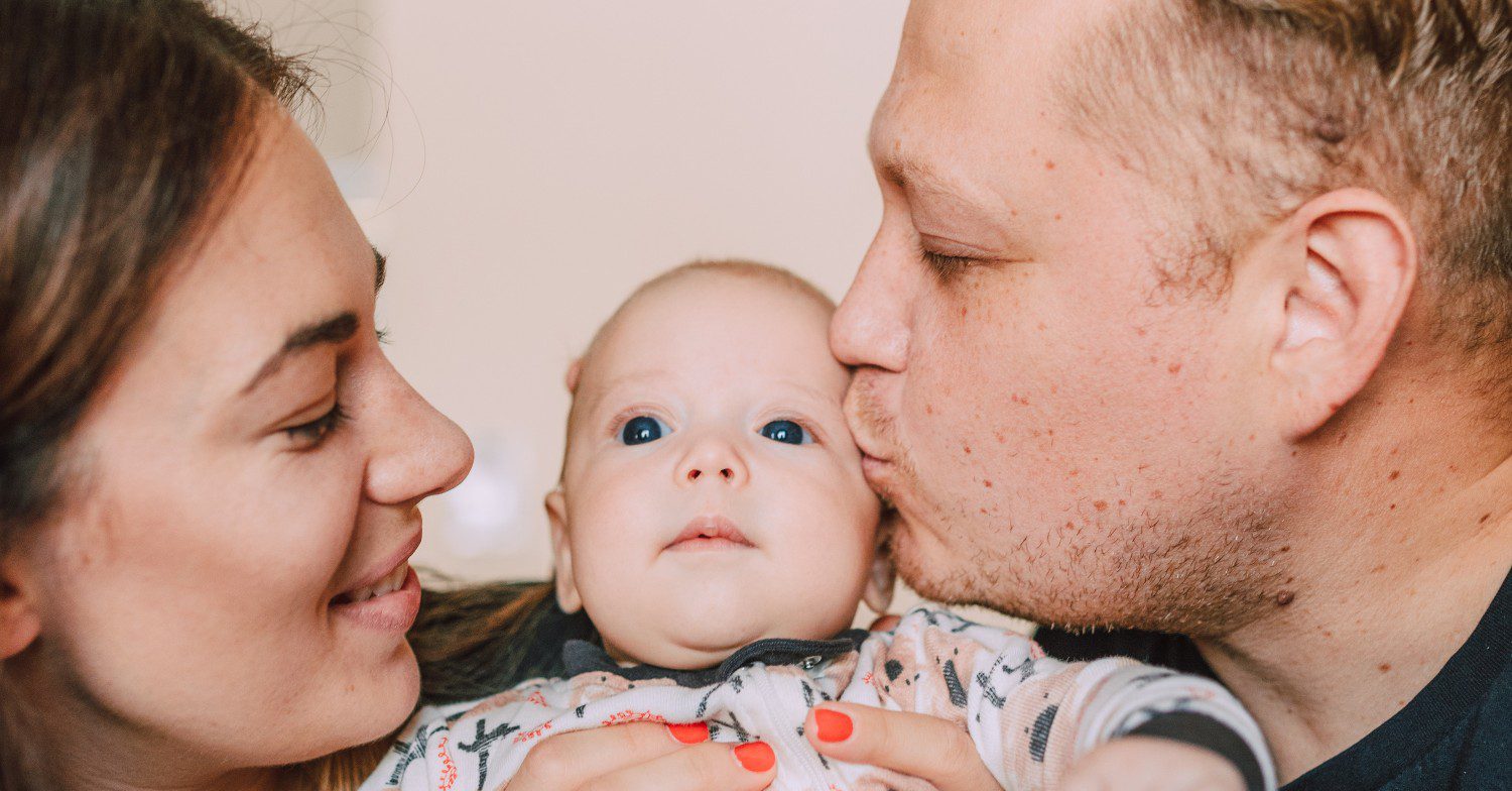 Parents kiss baby