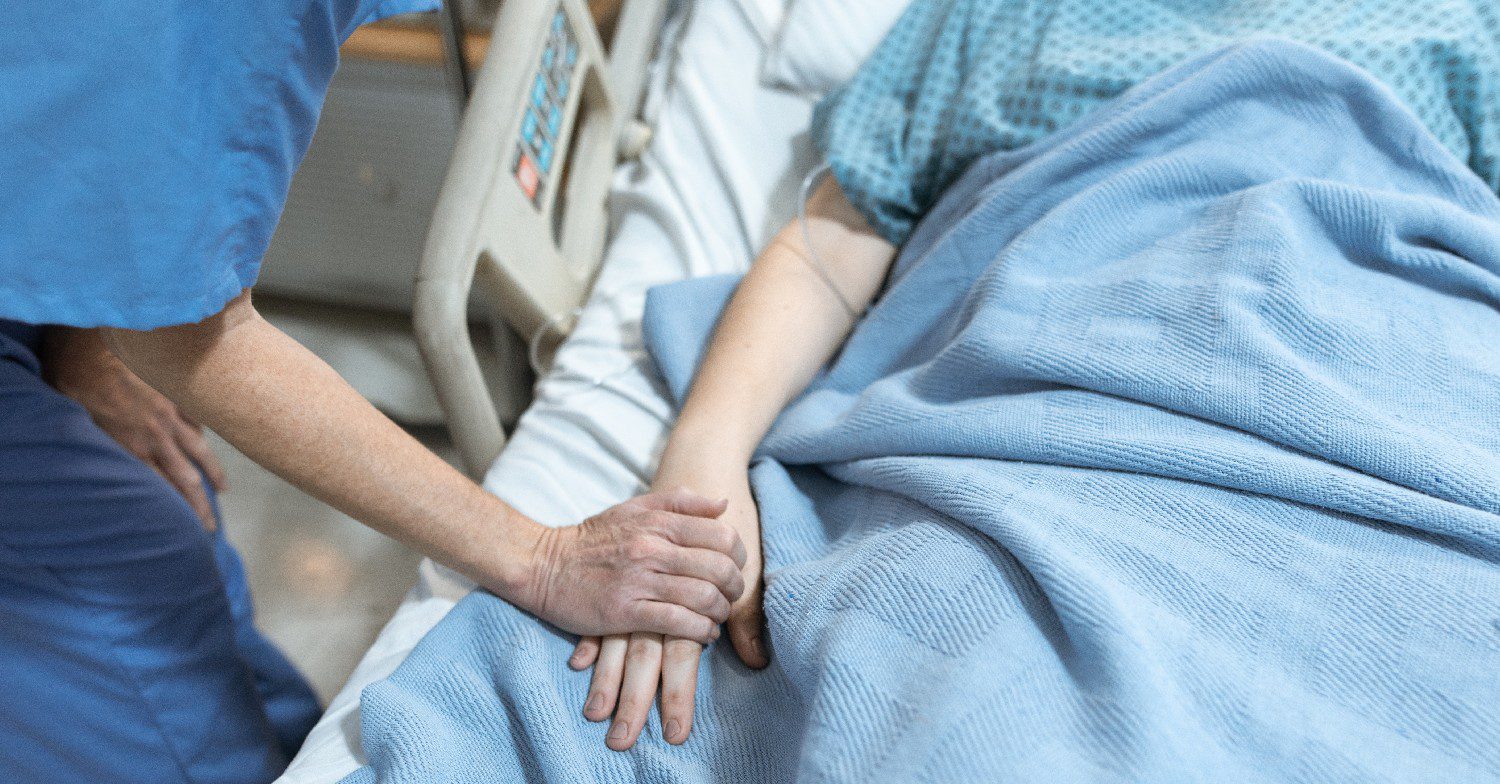 Nurse holding patient's hand in hospital