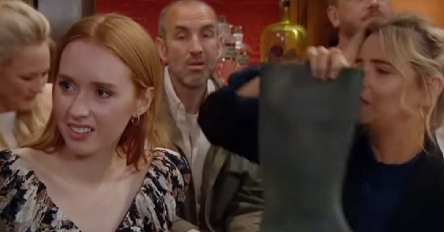Emmerdale's Chloe is looking away as Charity is holding a welly up in the pub