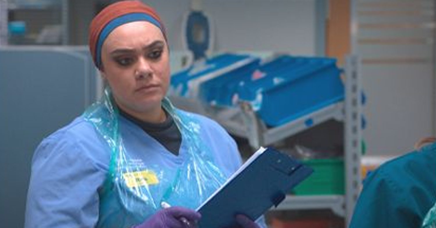 Casualty's Rida is holding a clipboard whilst looking concerned