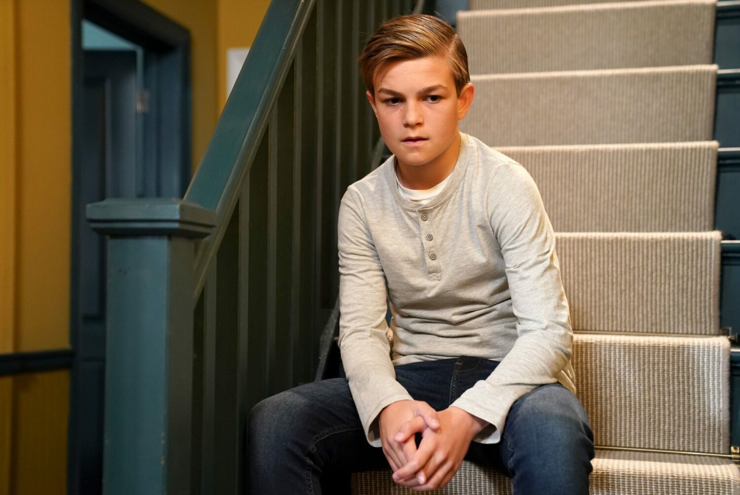 Tommy Moon looks intrigued on the stairs in EastEnders