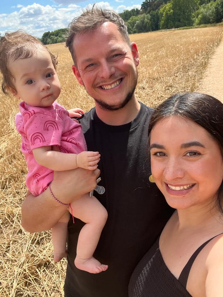 Young mum and dad with their baby girl in the sunshine