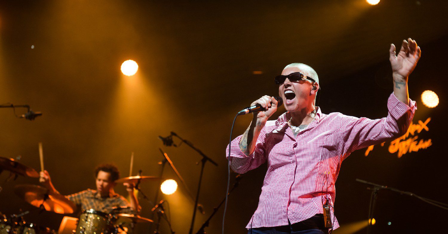 Singer Sinéad O'Connor in a red shirt singing live on stage
