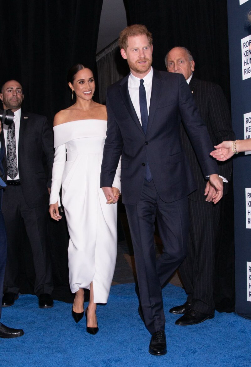 Meghan and Harry smiling and holding hands at event