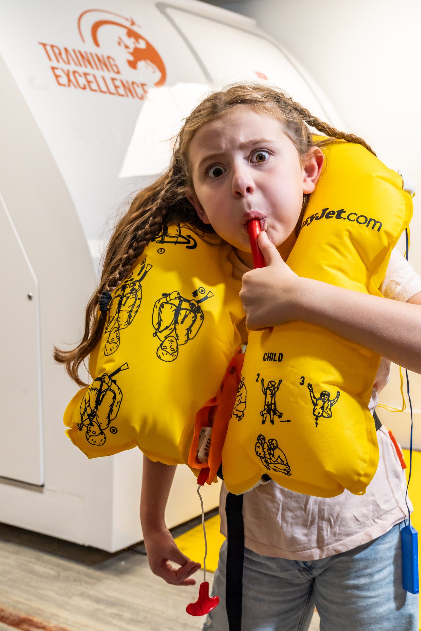 Child blowing on a whistle wearing a life vest