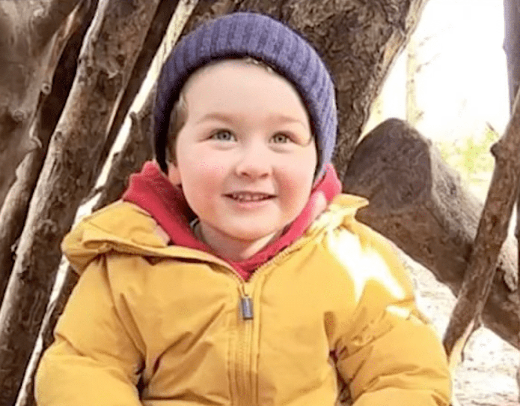 Little boy smiles in a yellow raincoat