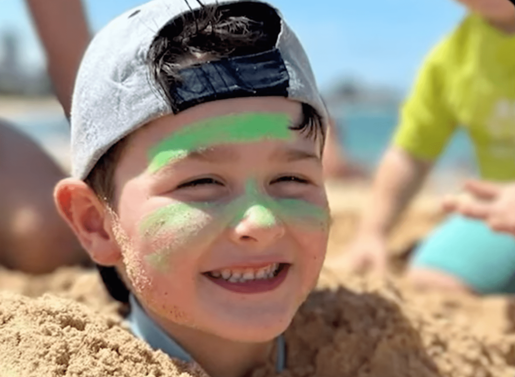 Little boy smiling buried in the sand
