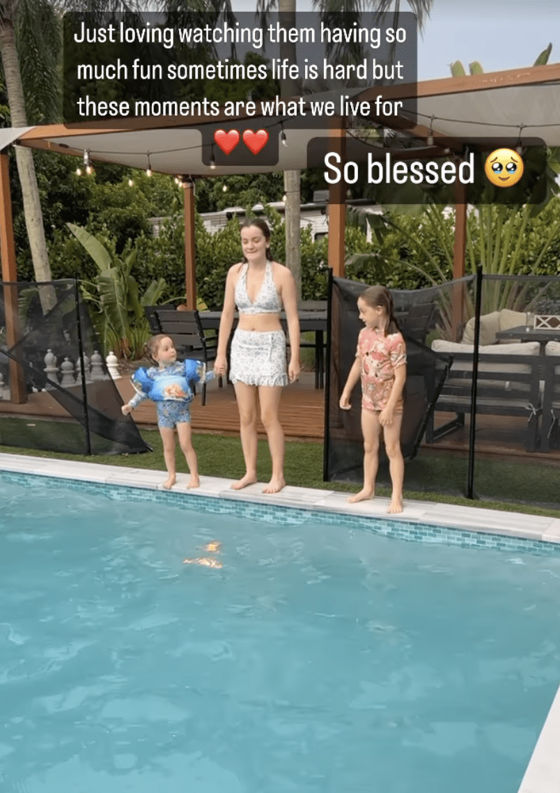 Three children standing at the side of a swimming pool