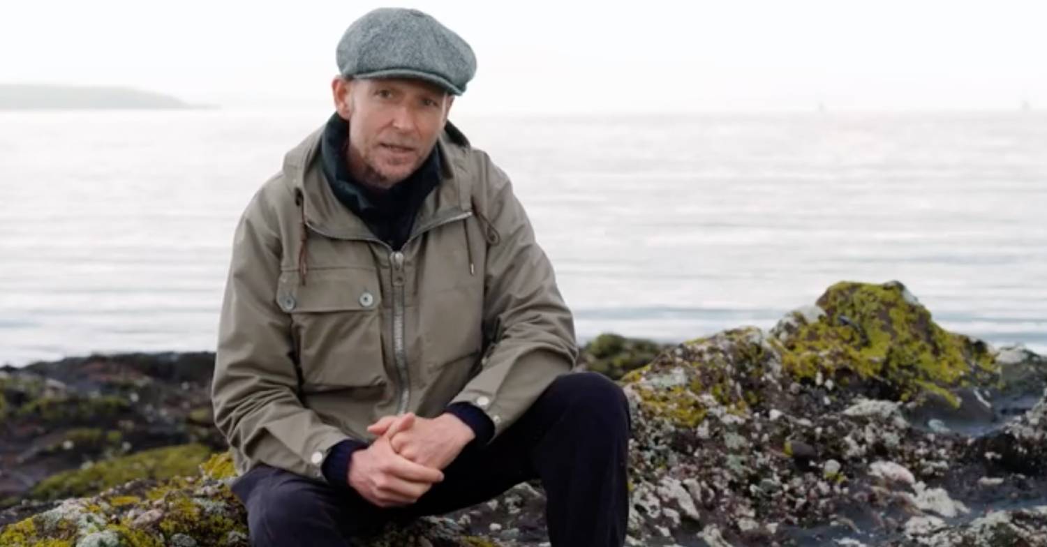 Jonnie Irwin sits near the coastline