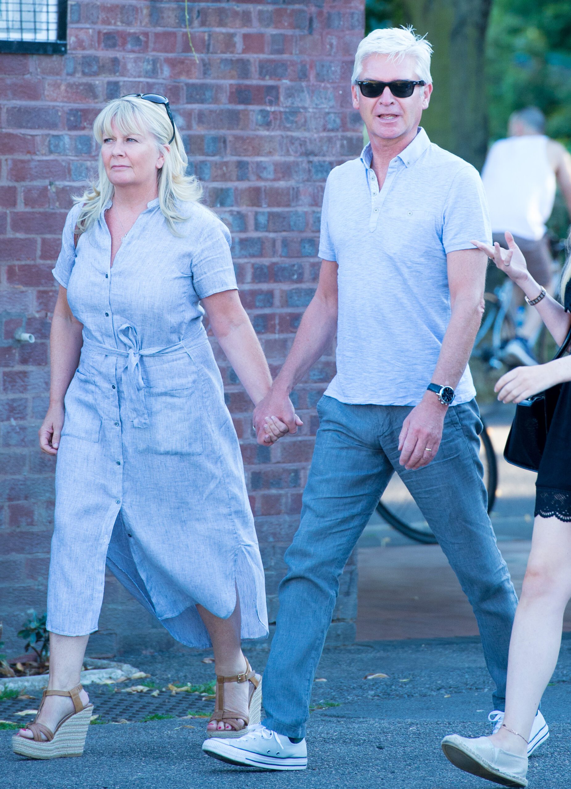 Phillip Schofield wearing sunglasses holding hands with his wife