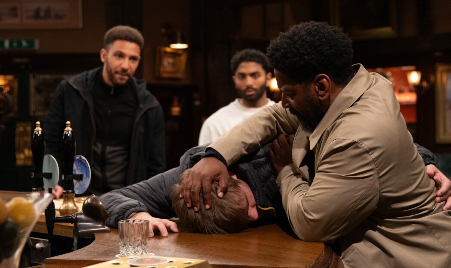 Charles pinning Tom's head down on the bar 