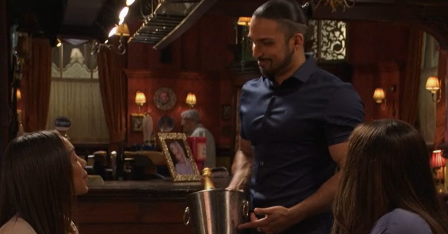 EastEnders' Ravi is holding a bottle in The Vic and is putting it on Chelsea and Denise's table