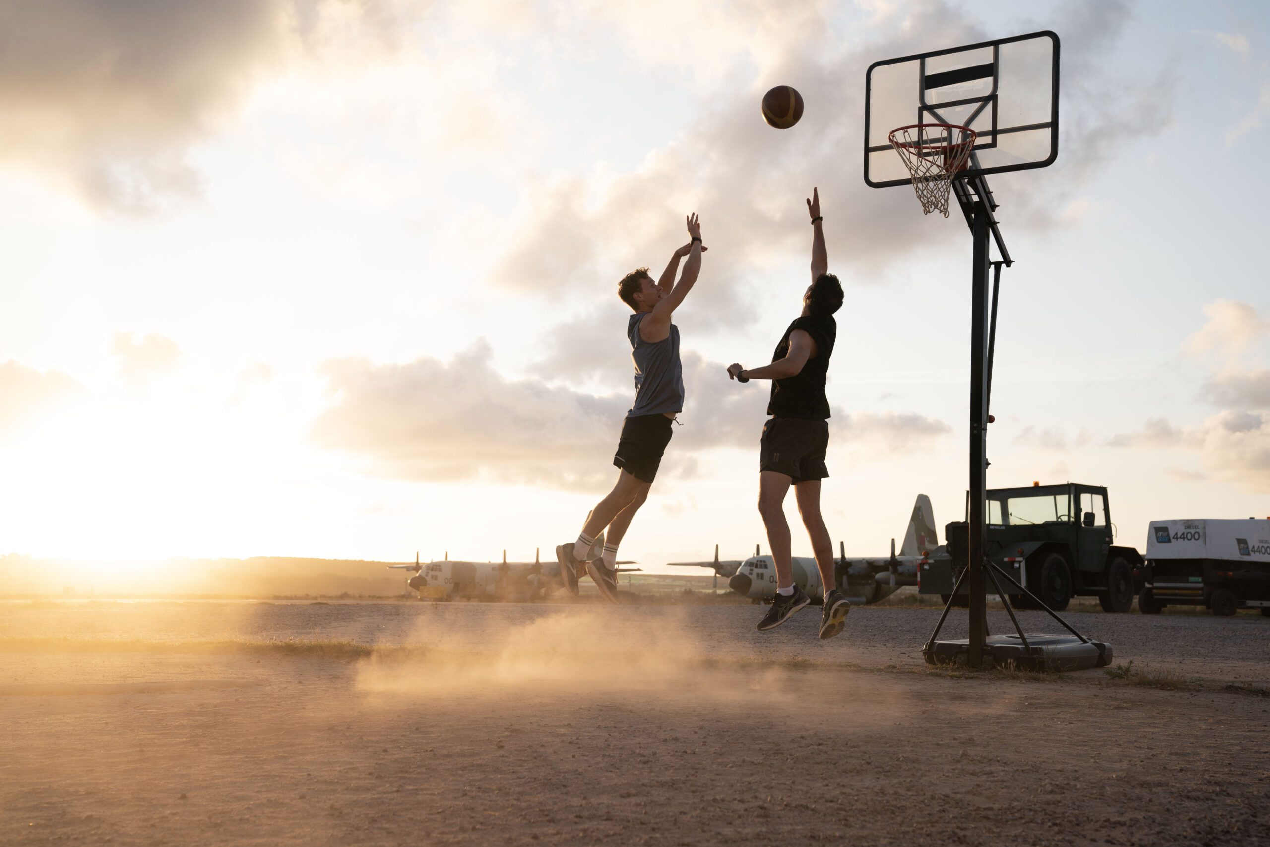 Two men playing basketball at sunset