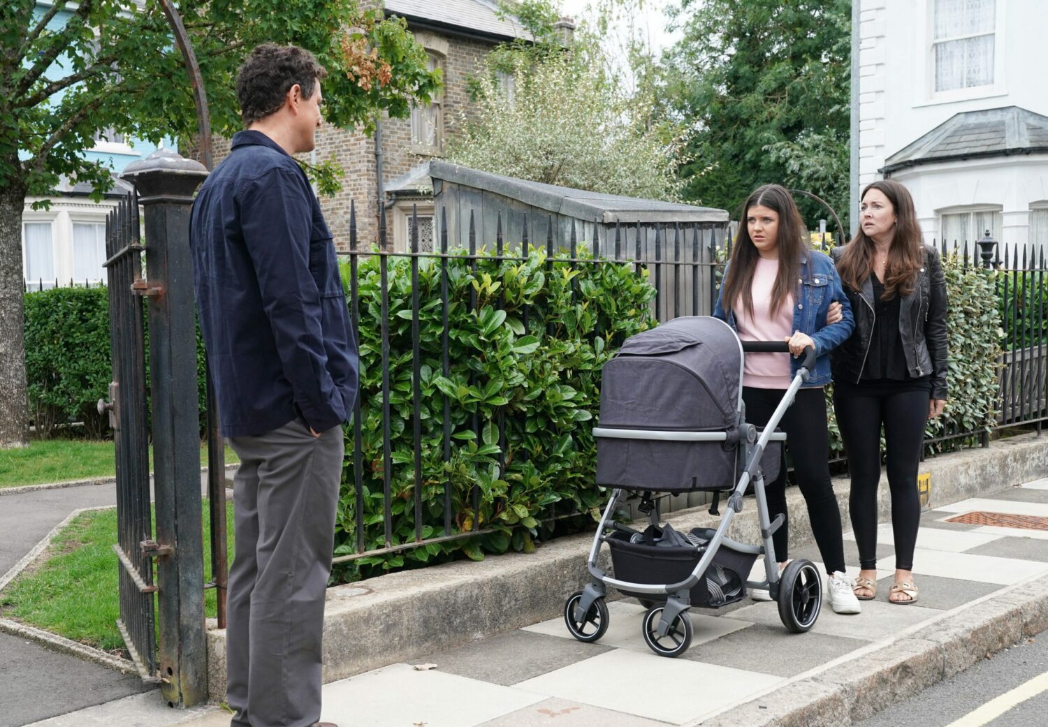 Lily and Stacey Slater look worried as they push the buggy and Theo Hawthorne blocks their path