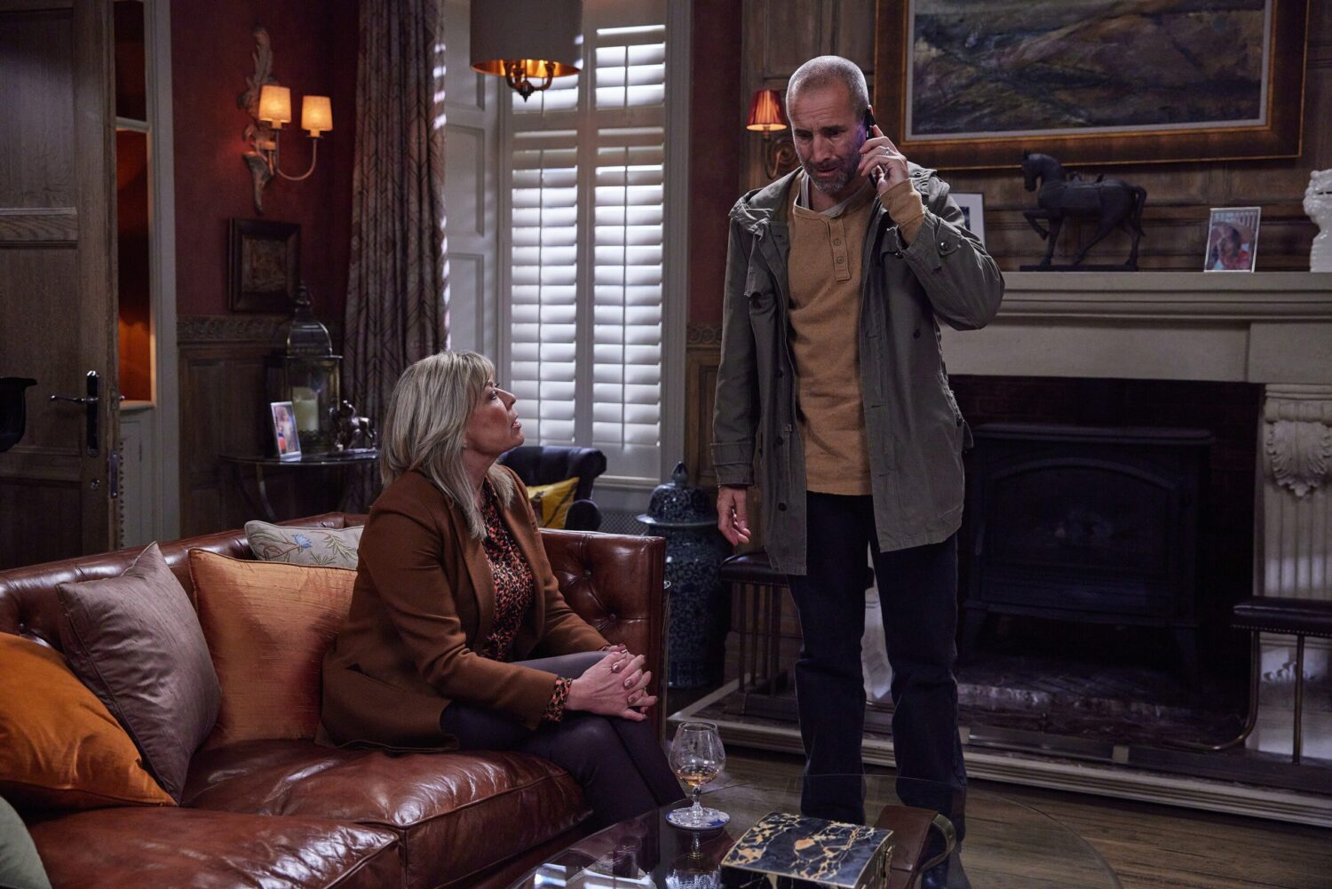 Sam on the phone as he sits with Kim Tate on Emmerdale