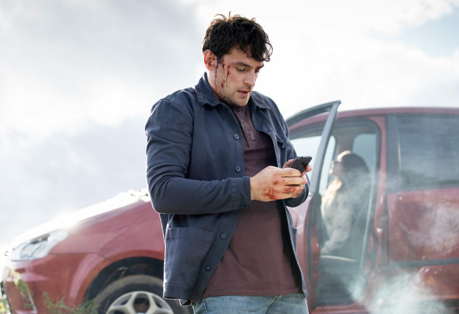 Emmerdale's Mack is outside the car, on his phone, with cuts on his face