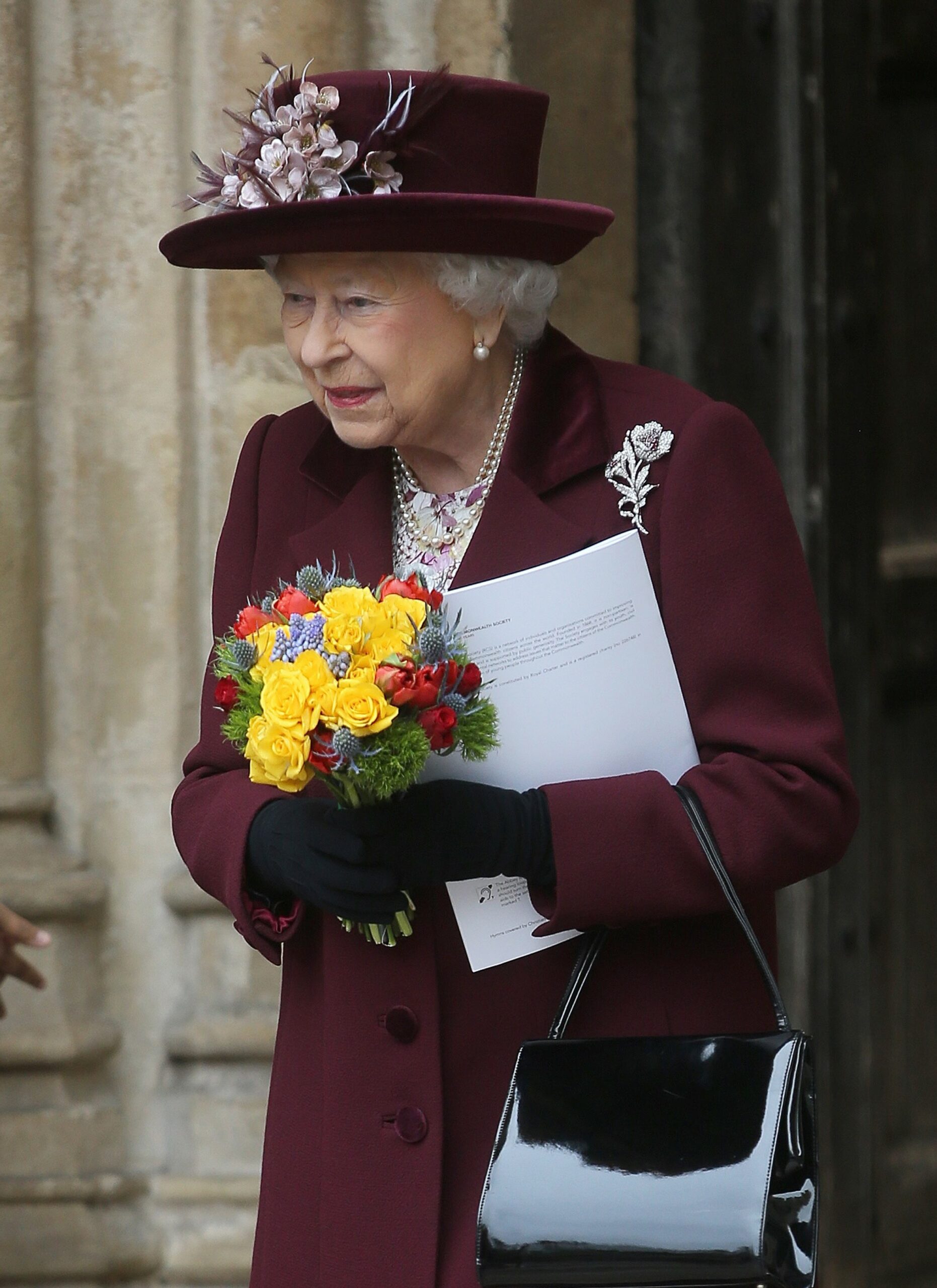 The Queen smiling in burgundy outfit