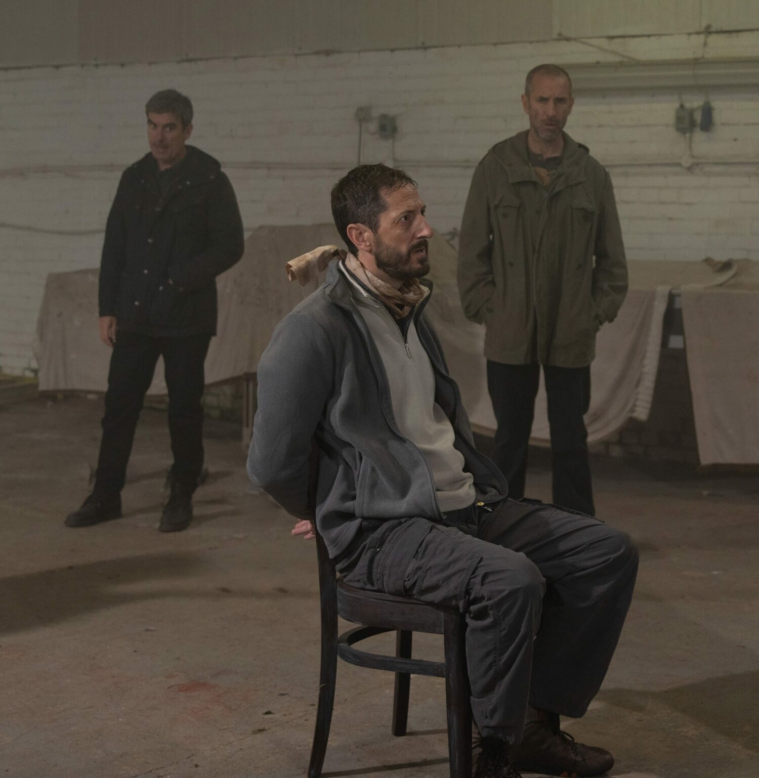 Craig looks scared, tied to a chair, while Sam and Cain look on (Credit: ITV)