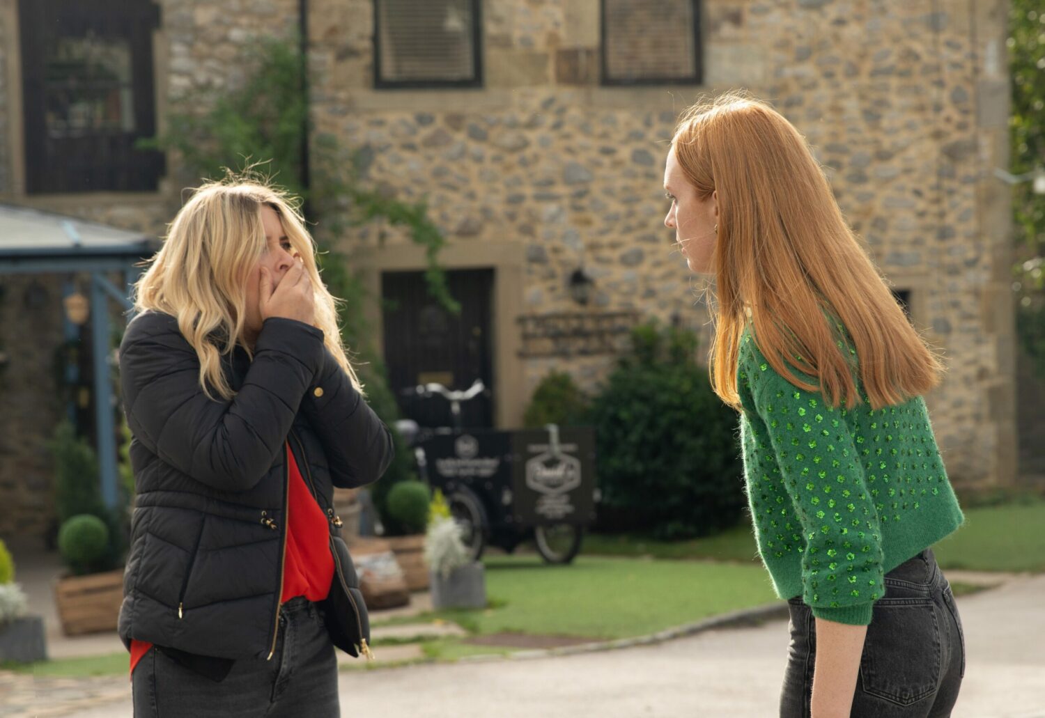 Emmerdale's Charity is holding her face as Chloe stares at her