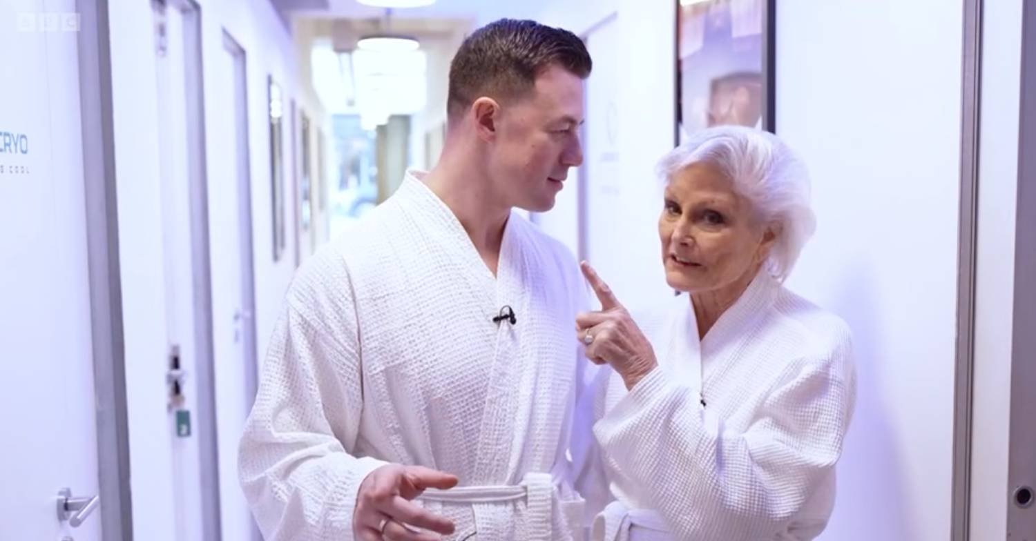 Strictly star Angela Rippon points at partner Kai as they both wear white dressing gowns